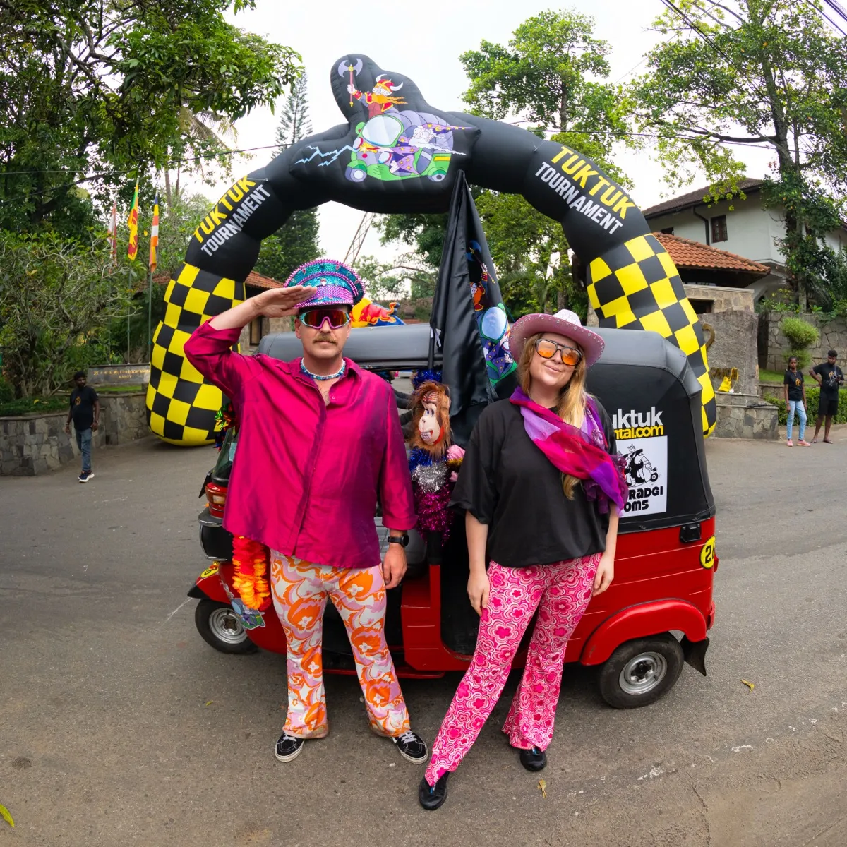 Retro-dressed couple posing at the TukTuk Tournament starting arch